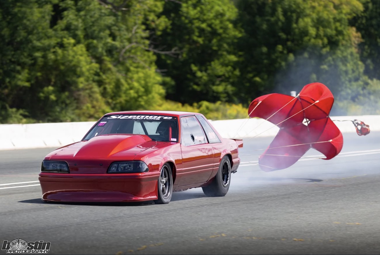 Red drag car deploying its parachute after a pass