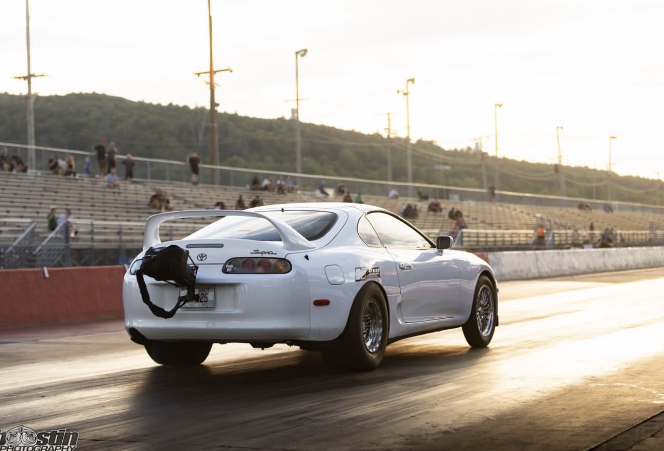 White Toyota Supra racing down the drag strip